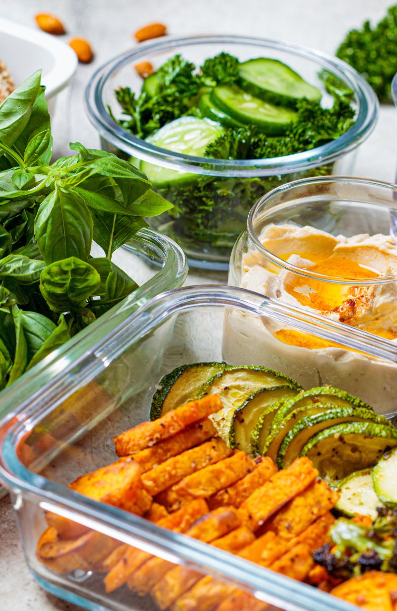 Batch-cooking-repas-préparés Tupperwares en verre avec des repas préparés pour la semaine à base de courgettes, patates douces, basilic, brocoli, houmous